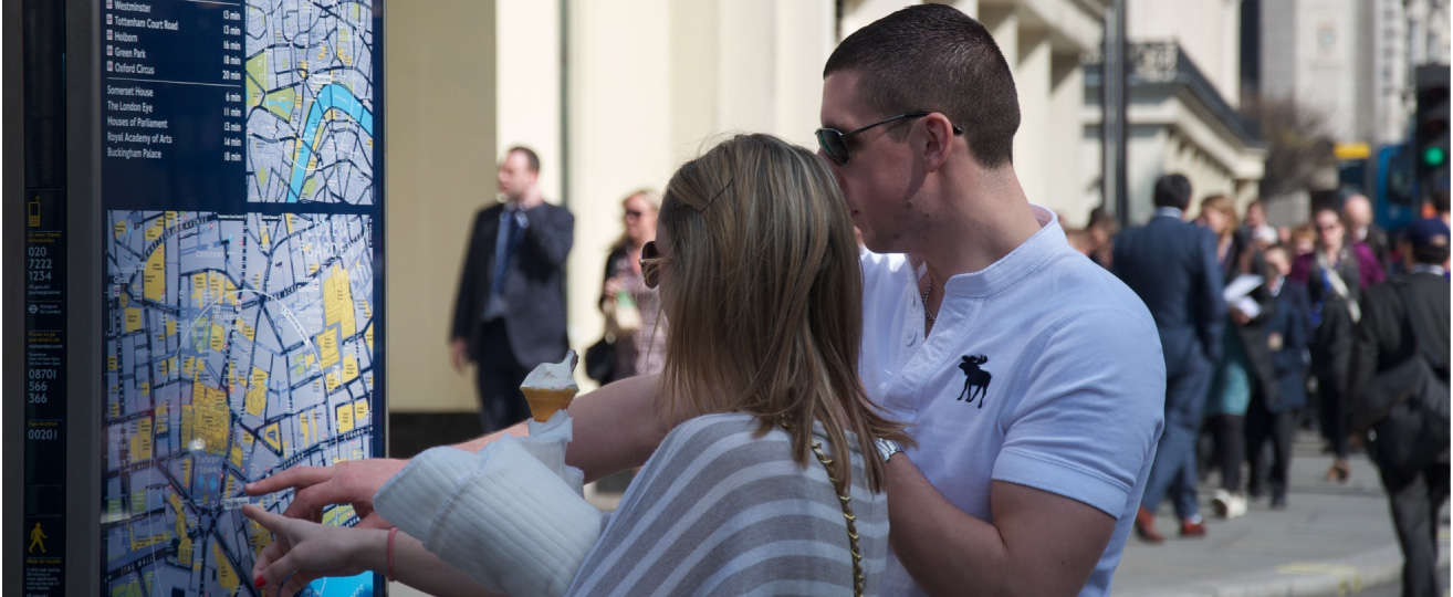 A photograph shows two people on a city street looking at a map.