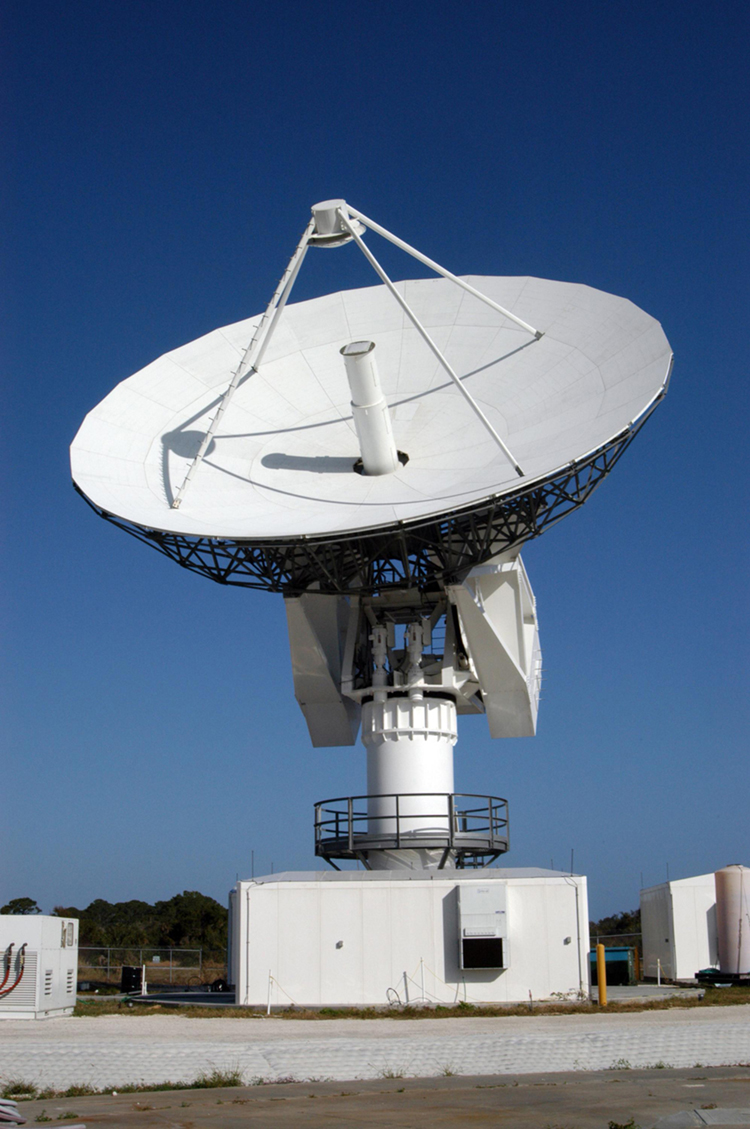 The large, round dish antenna looking like a giant white saucer is shown. It rests on a pillar shaped structure with a moveable tracking system that allows it to point towards a target object, send out electromagnetic waves, and collect any signals that bounce back from the target object. 